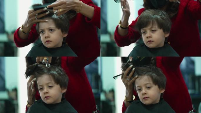 小孩在发廊理发的特写镜头。专业发型师为小男孩剪发梳理，神情严肃沉思