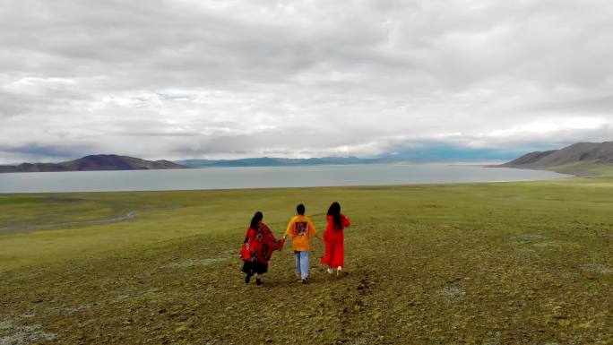 航拍旅行女孩在西藏草原上向湖面奔跑4K