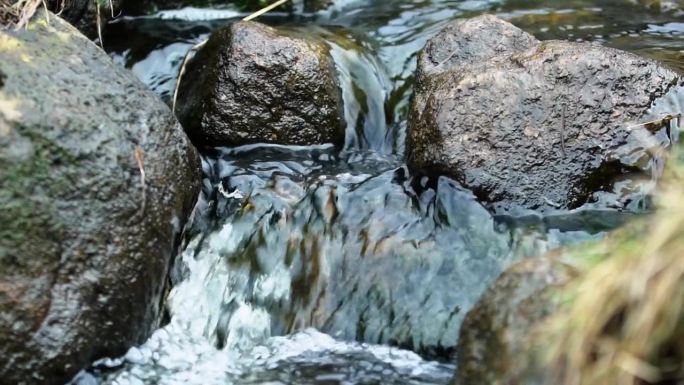 高帧率的水的溪流流过一些岩石的镜头。在苏格兰外赫布里底群岛的刘易斯岛拍摄。