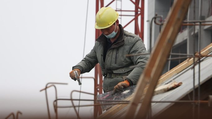 工地上民工正在钉木板维修房顶