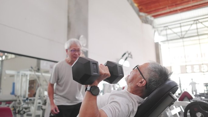 亚洲老年男子鼓励老年男子在健身房练习重量训练