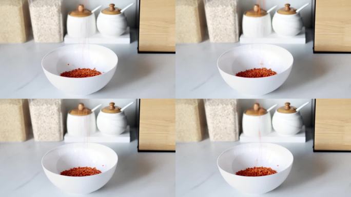 红色的扁豆被倒入白色的盘子里，背景是现代厨房的慢动作。健康食品和营养理念。安全、生态、健康产品