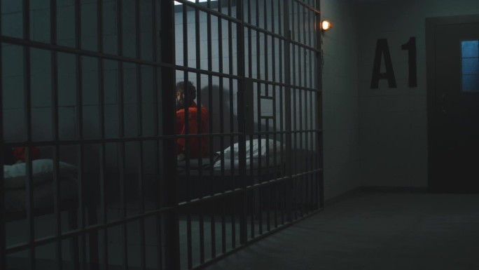 有罪的罪犯躺在监狱牢房的床上或坐在床上