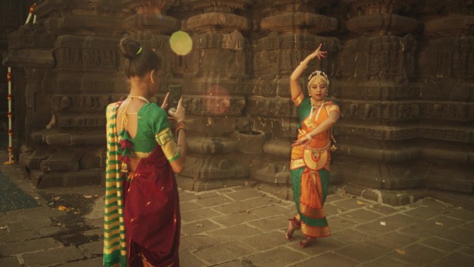 一位朋友用智能手机拍摄了穿着传统服装的印度妇女穿着彩色纱丽跳舞的动态镜头。年轻女性分享民间舞蹈和她的