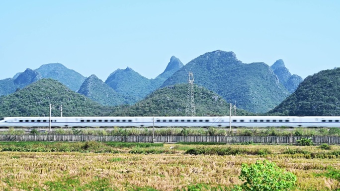 万里无云天空下桂林山边铁路上的高铁动车