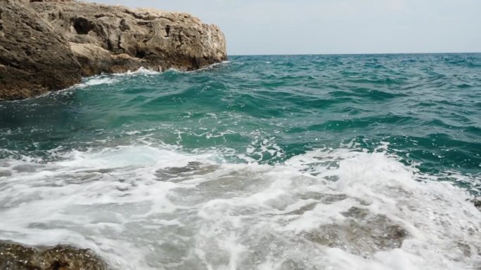 汹涌的大海和蓝绿色的海浪，泡沫撞击着海岸的岩石。