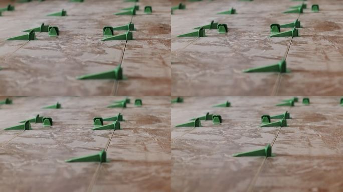 瓷砖找平系统，四个带楔子的塑料绿色夹子。特写镜头，选择性对焦，背景模糊。