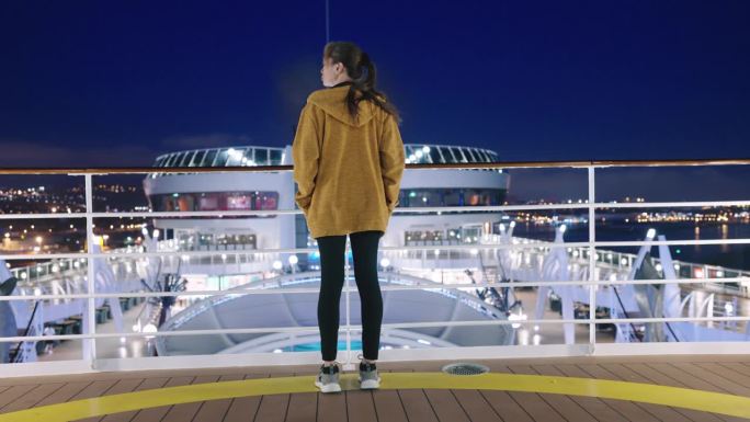 晚上在甲板上享受旅游假期的女游客。