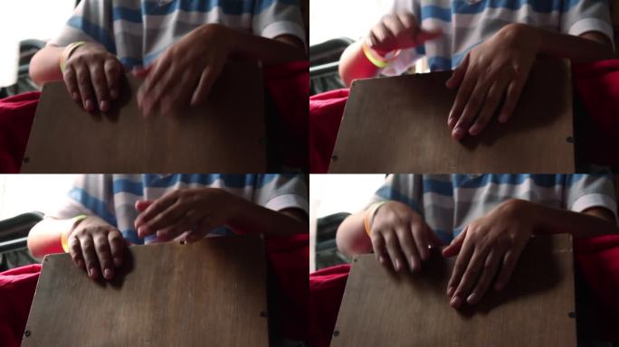 年轻的打击乐手正在演奏一种来自秘鲁的传统盒子形状的打击乐器，叫做"Cajon Peruano"(秘鲁