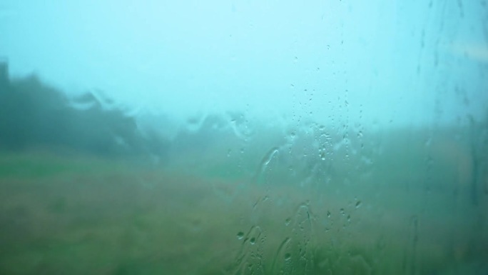 大雨中透过火车窗户看到的景象。雨滴顺着窗玻璃流下来。火车窗外下着大雨。在雨中乘火车去山里旅行的梦幻气