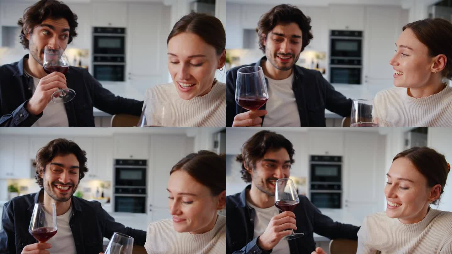 年轻夫妇在家里的厨房里喝着红酒，边说边笑
