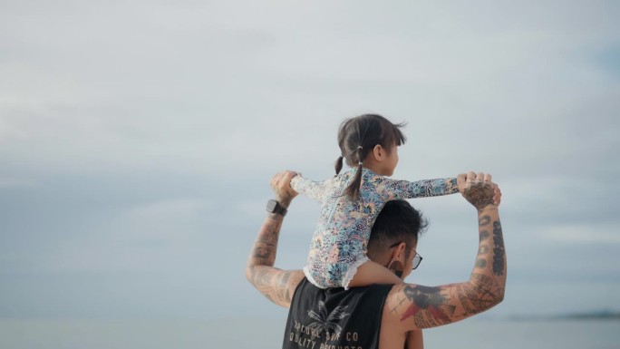 一个快乐的时刻，一个父亲和他的女儿在日落的海滩上散步。