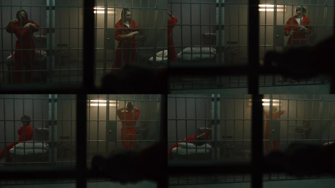 两名女囚犯站在监狱牢房的铁栏后面走动