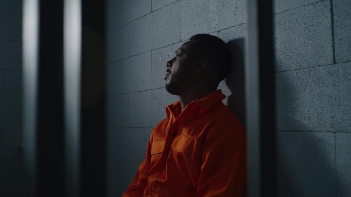 有罪的非裔美国人坐在监狱的床上