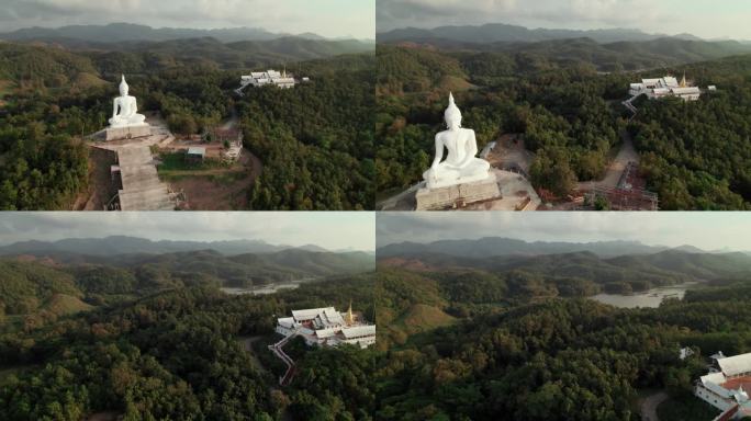 位于佛教寺院附近的佛像鸟瞰图，周围环绕着绿色的森林和山脉，是灵性和宁静的宗教旅行场所