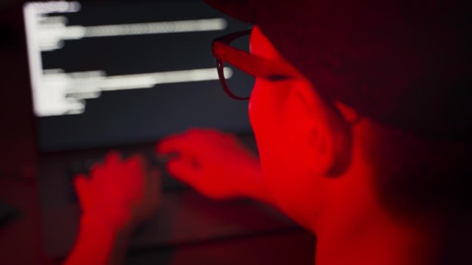 在暗室里靠近黑客的背影，试着用红色应急灯编程入侵电脑。