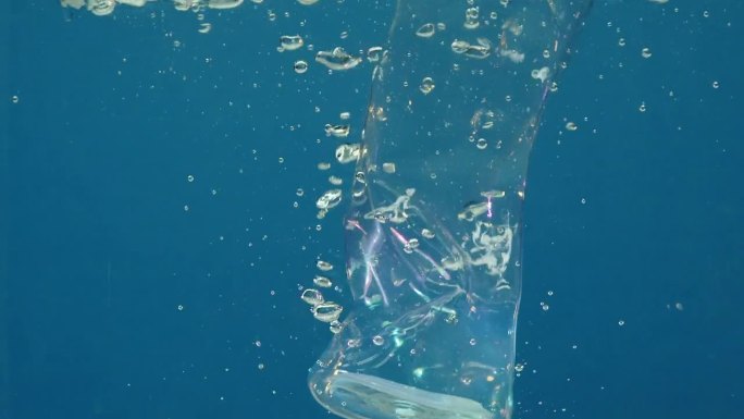 水下的慢动作镜头描绘了未经处理的塑料，金属碎片下降，气泡上升。废物下沉，加剧了全球生态问题