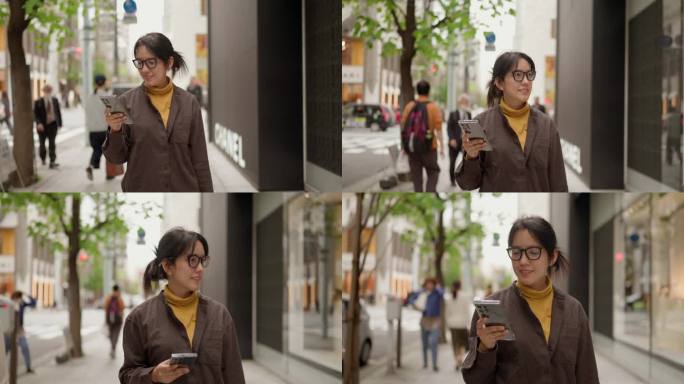 一位职业女性，穿着休闲，走在城市的街道上，看着她的智能手机。