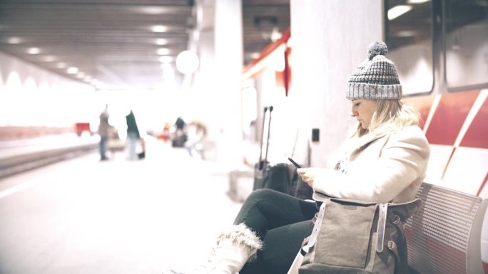 一名女子在等火车时使用智能手机