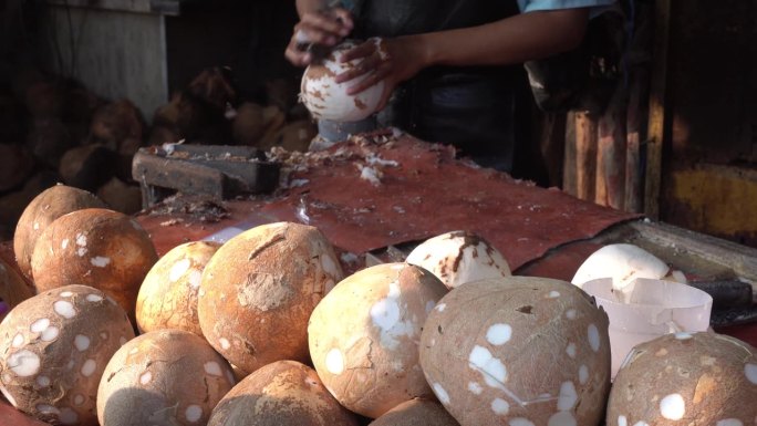 水果商人剥去椰子的皮并清洗干净。传统市场商店里商人的气氛