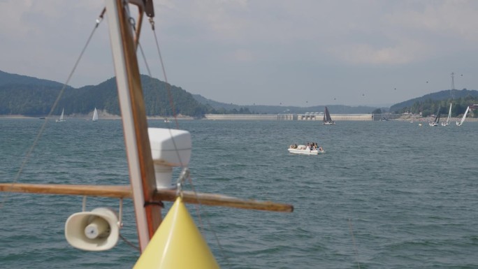 暑假在湖边。船上桅杆在水面上的特写。骑着脚踏船路过的人