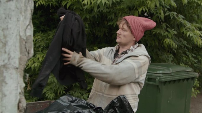 衣衫褴褛的人在垃圾堆里找衣服