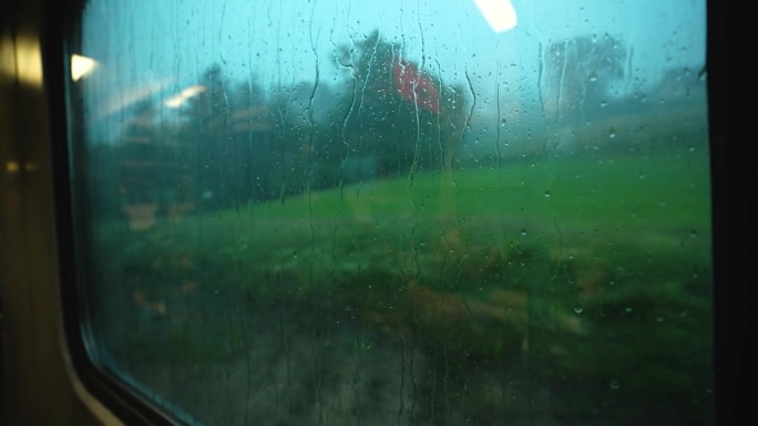 大雨中透过火车窗户看到的景象。雨滴顺着窗玻璃流下来。火车窗外下着大雨。在雨中乘火车去山里旅行的梦幻气