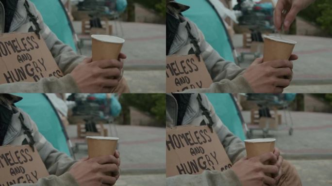 无家可归者举着牌子，举着杯子，请求捐赠