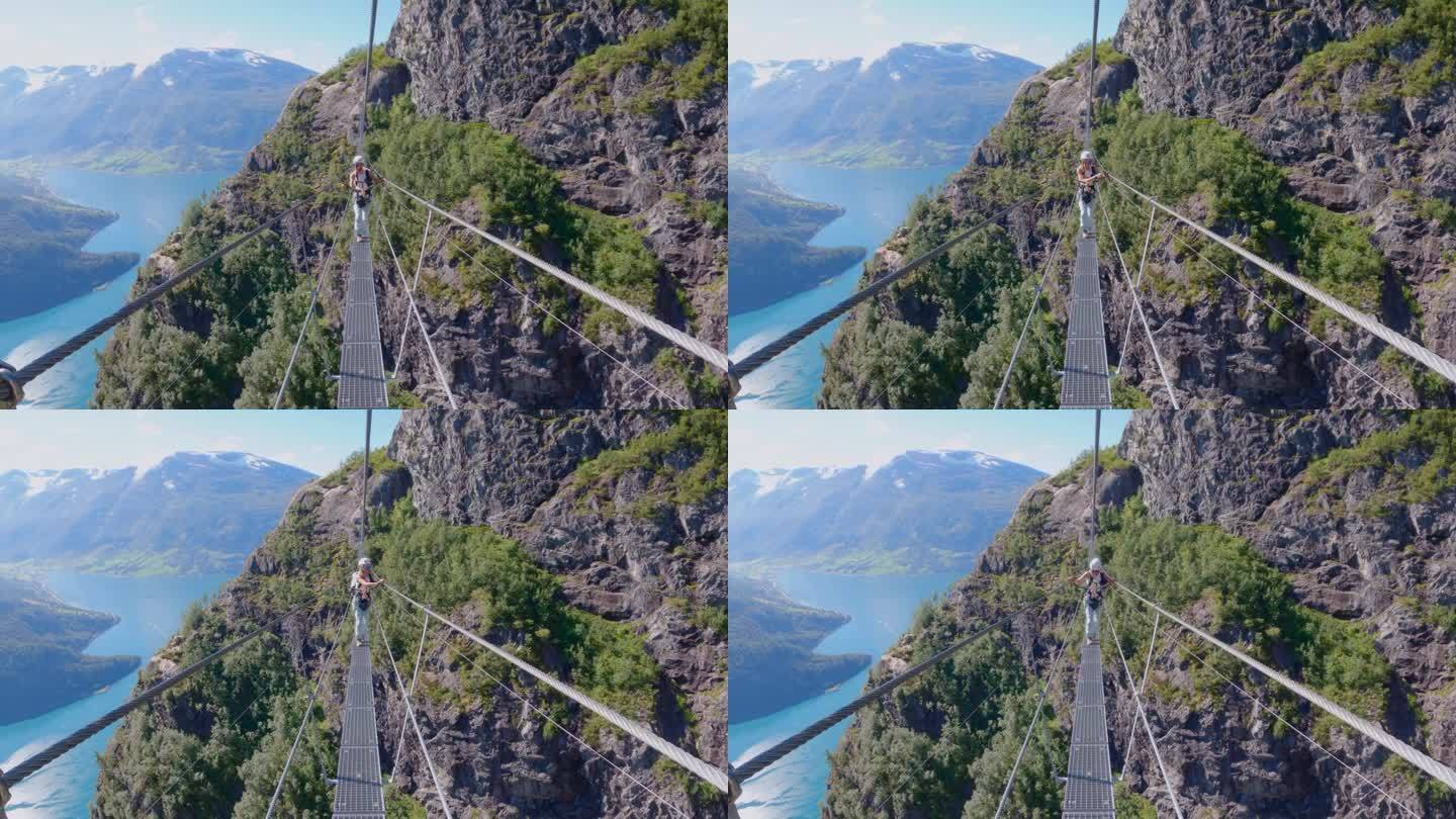 一名女子走在挪威的费拉塔之路上的吊桥上