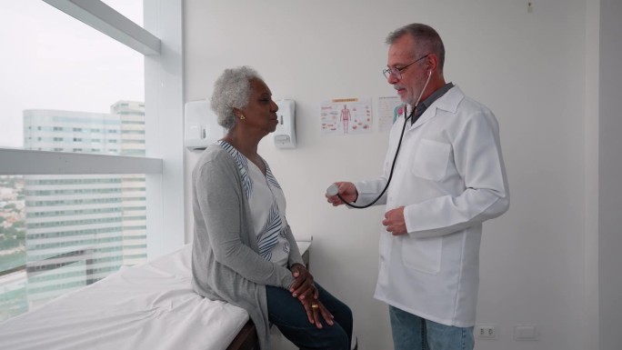 一幅医生聆听一位老年妇女病人心跳的画像