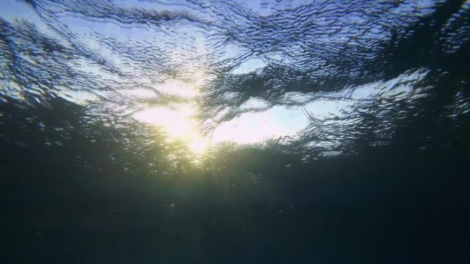 阳光穿透起伏的海面，在水柱上形成明亮的光束。