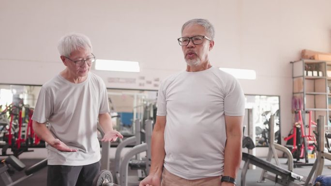 亚洲老年男子鼓励老年男子在健身房练习重量训练