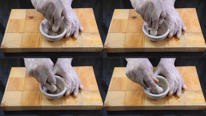 用研钵和杵研磨黑胡椒，近距离拍摄一位老人用瓷泥研钵和杵手工研磨黑胡椒