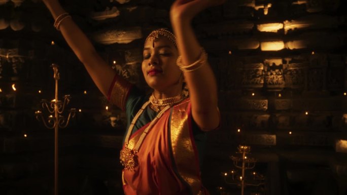 一个穿着传统服装的活跃的印度女舞者在一座古老的寺庙里的慢动作肖像。她展示了Bharatanatyam