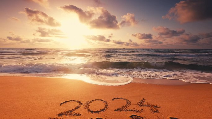 海面上的日出和迎接2024年新年的文字写在沙滩岸边的沙子为自然背景
