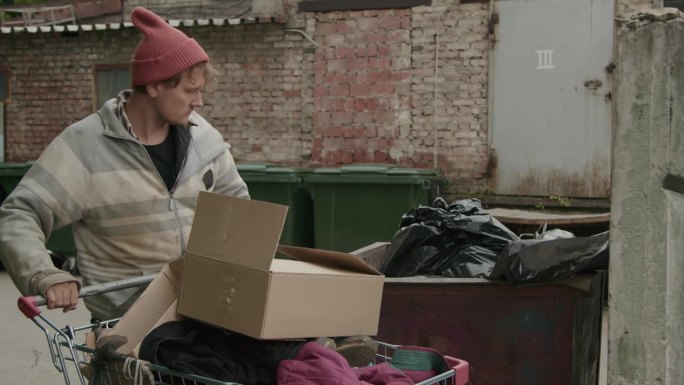 乞丐从垃圾桶里拿出装有香蕉的盒子
