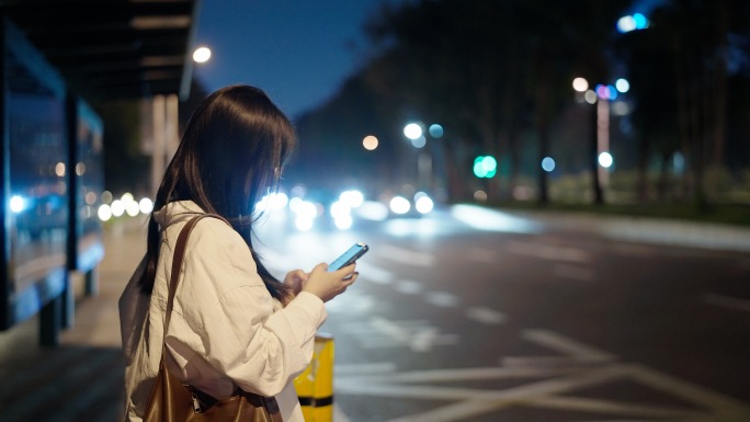 夜晚女孩等公车玩手机