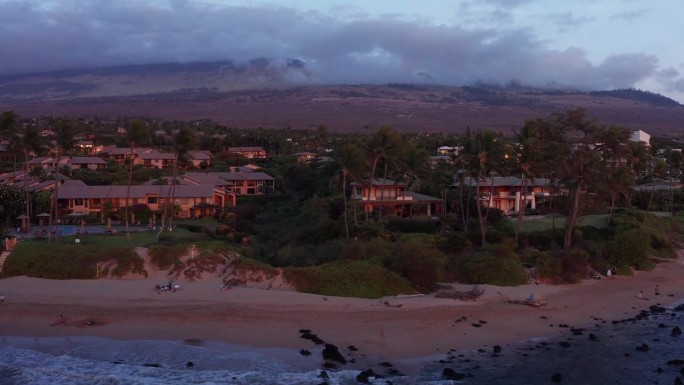 在夏威夷南毛伊岛日落时，沿着威利海岸的豪华海滩度假村的特写摄影车航拍。4 k