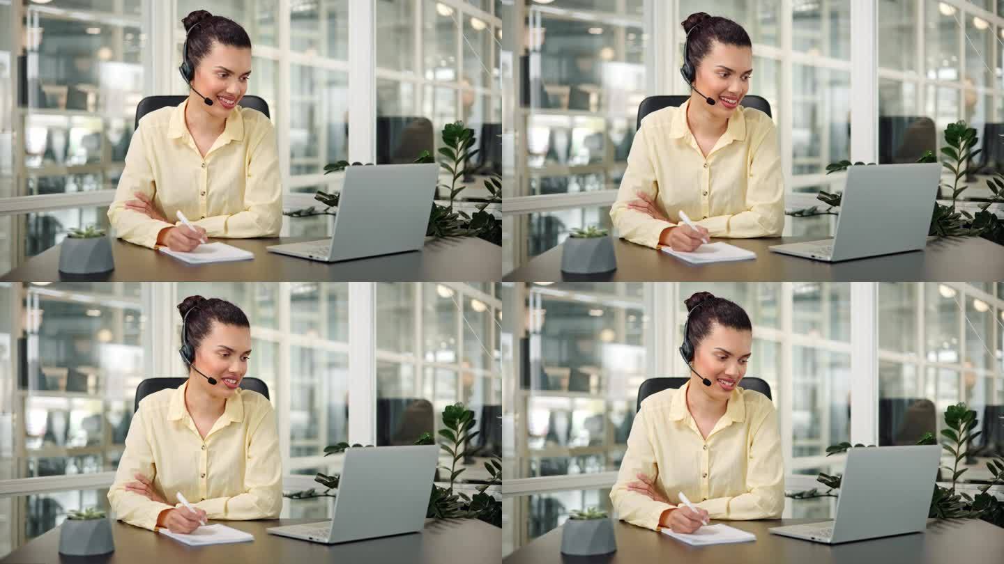 友好的女商人戴着无线耳机在笔记本电脑上进行视频会议。女性专业呼叫中心座席，人力资源经理在办公室用电脑