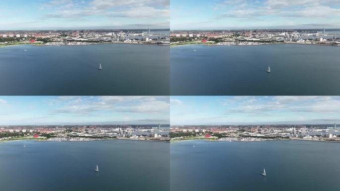 一艘帆船巡游丹麦奥胡斯湾-夏季航拍全景城市背景