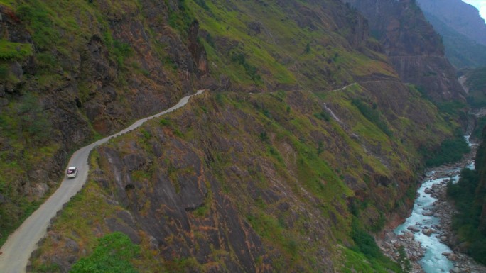 空中鸟瞰与游客一起驾驶的四轮驱动汽车在通往马南的山路上上坡。公路旅行在喜马拉雅山脉的安纳普尔纳山脉。