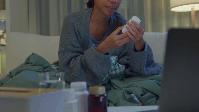 亚洲年轻女孩患者的特写，在笔记本电脑上咨询医生视频通话，在应用程序上进行药物剂量说明，夜间在家远程医