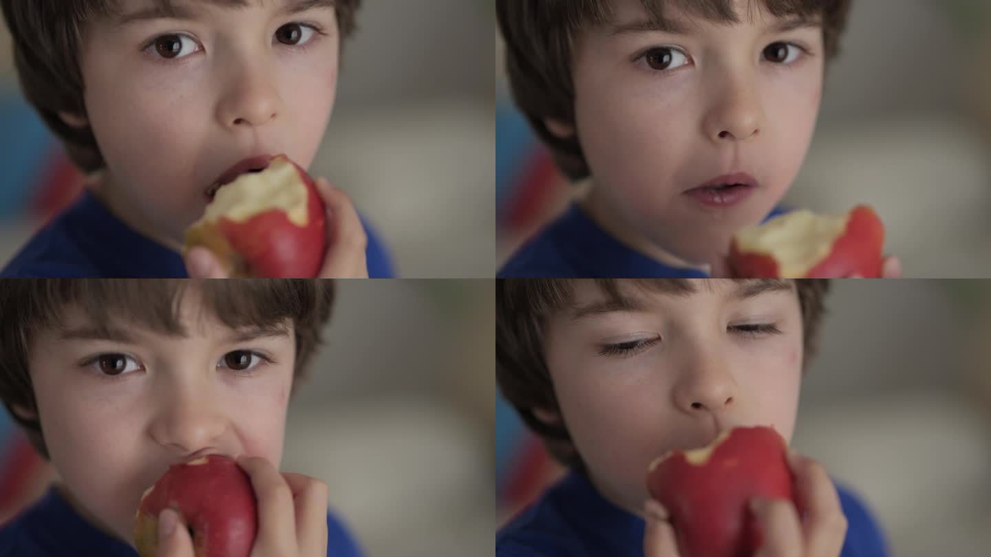 可爱的小男孩吃红苹果。孩子吃水果。小孩一边咬水果一边嚼，看着厨房里的照相机。健康饮食素食者。健康营养