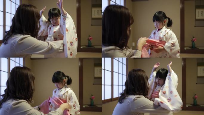 母亲给小女儿穿衣服，准备参加日本传统的生活活动——系腰带