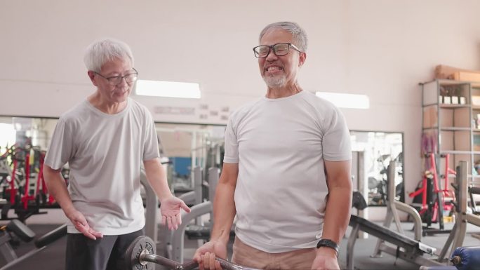 亚洲老年男子鼓励老年男子在健身房练习重量训练
