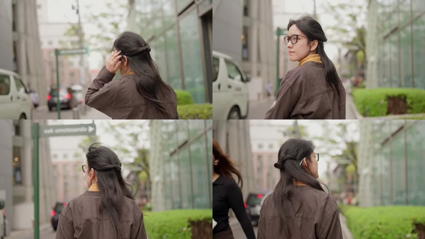 快乐的亚洲女孩戴着眼镜走在街上，在城市里环顾四周。