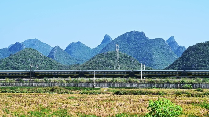 万里无云天空下山边铁路上行驶的客运火车