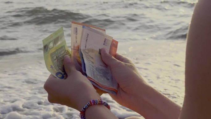 一个人拿着一把现金欣赏海景的照片