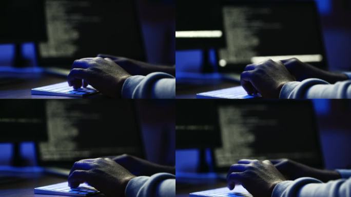 黑客在黑暗的办公室里用电脑键盘打字的特写镜头