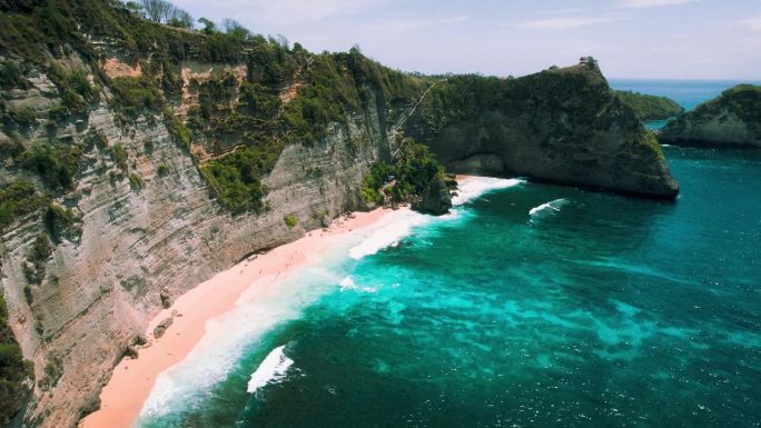 巴厘岛钻石沙滩上的山崖。原始的海浪与蓝绿色的水。